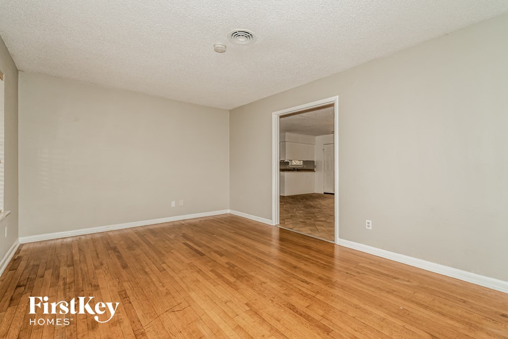 a spacious living room with hardwood flooring and a doorway to the kitchen
