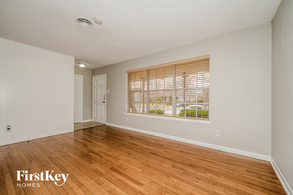 an empty living room with wood floors and a window