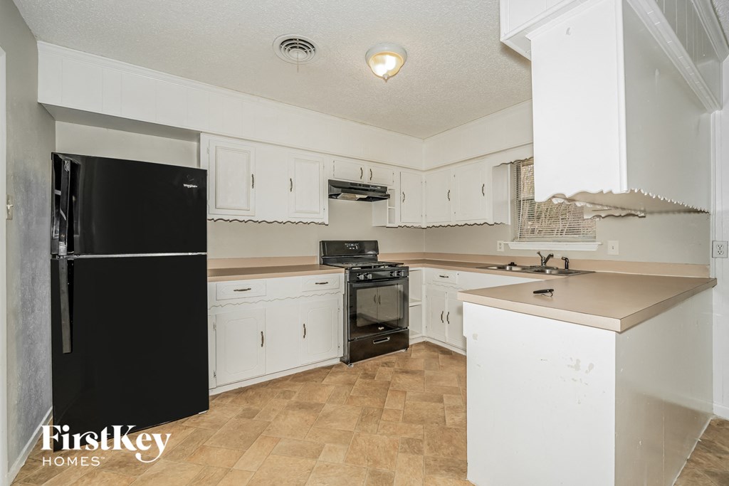 a kitchen with white cabinets and a black refrigerator