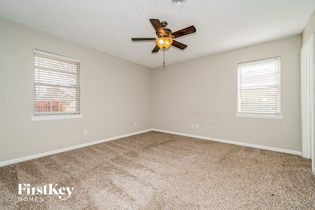 an empty room with a ceiling fan and two windows