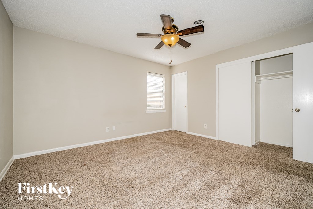 a spacious living room with carpet and a ceiling fan