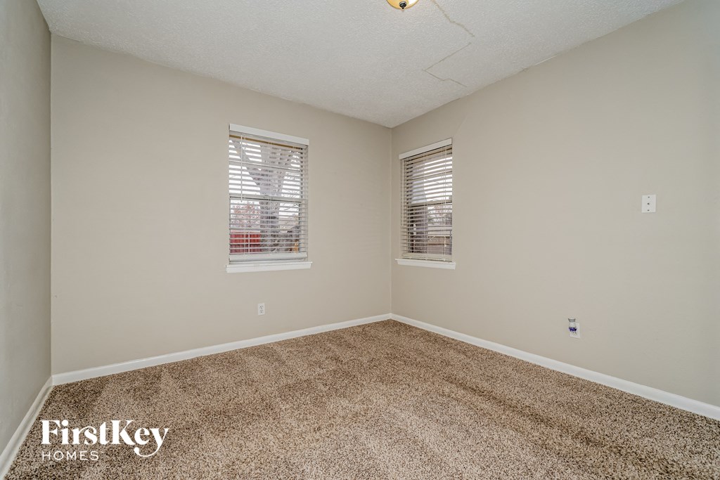 the spacious bedroom with carpet and two windows