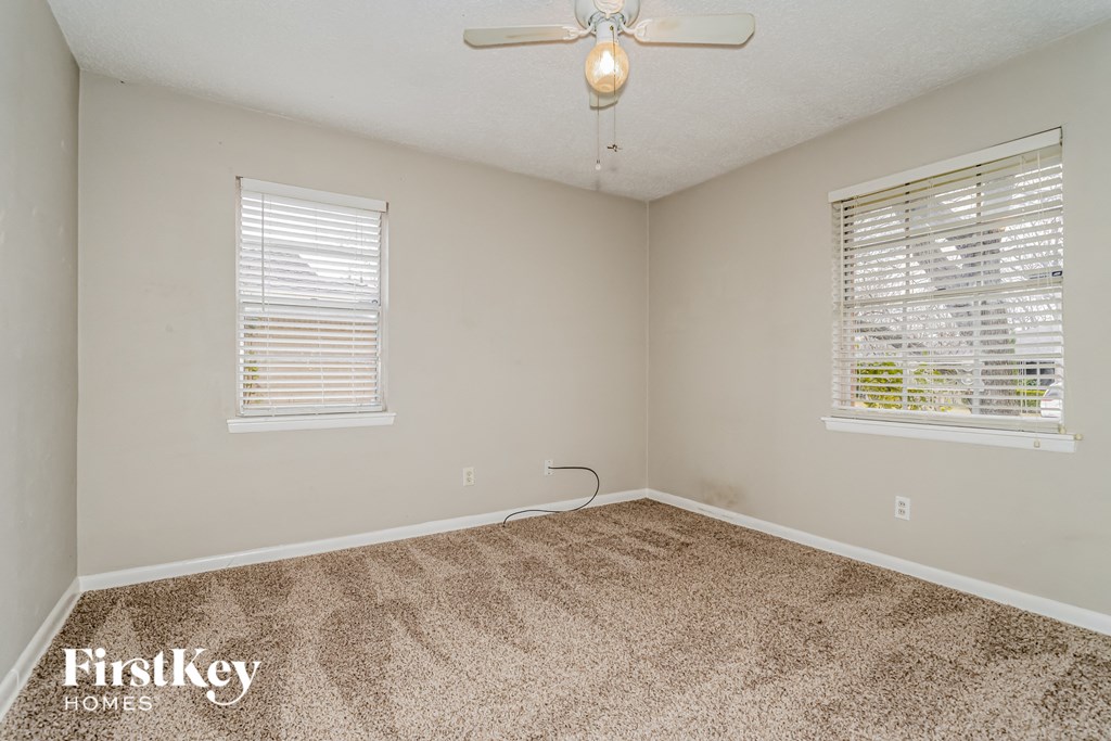 the living room of a home with carpet and a ceiling fan