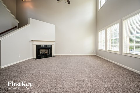 A spacious living room with a fireplace and a carpeted floor.