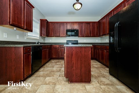 A kitchen with wooden cabinets and a black refrigerator.