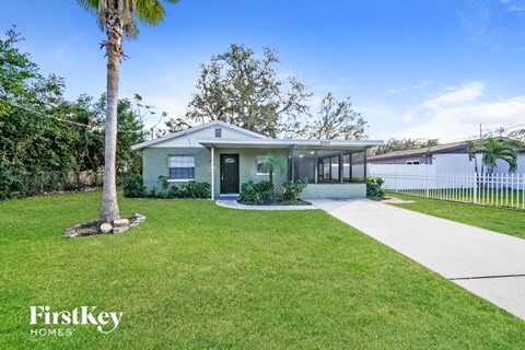 a house with a lawn and a sidewalk and a palm tree