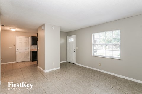 the living room and dining room of a house with a large window and tile floor