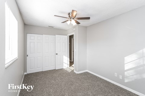 a bedroom with a ceiling fan and a door to a closet