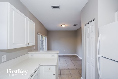 A kitchen with white cabinets and a white fridge.