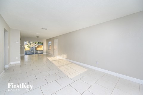 A spacious room with white walls and floor tiles.