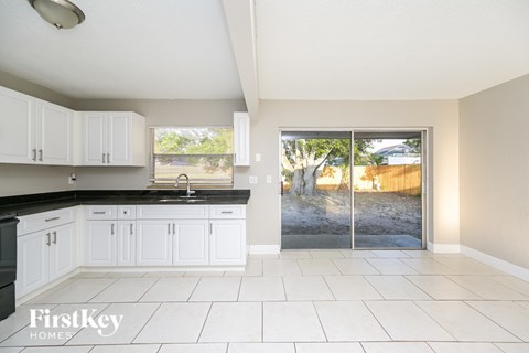 A kitchen with white cabinets and a black countertop.