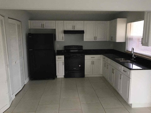 A kitchen with black appliances and white cabinets.
