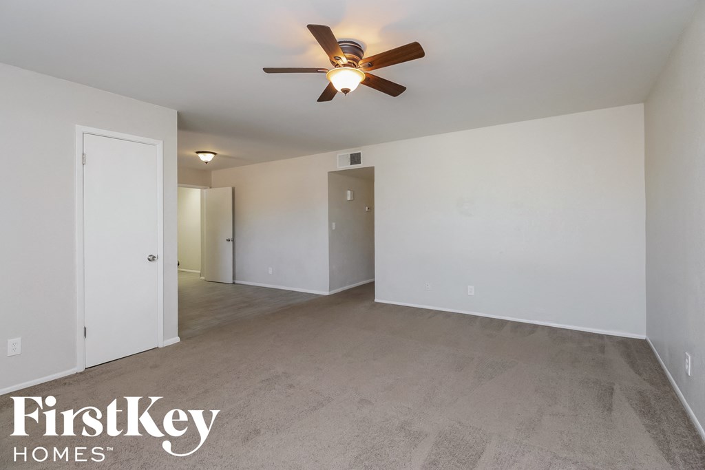 an empty living room with a ceiling fan and white walls