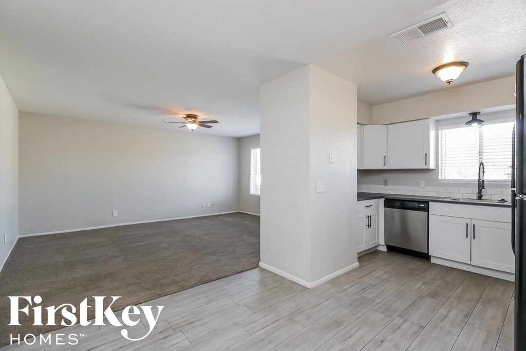 a kitchen and living room with white cabinets and a ceiling fan