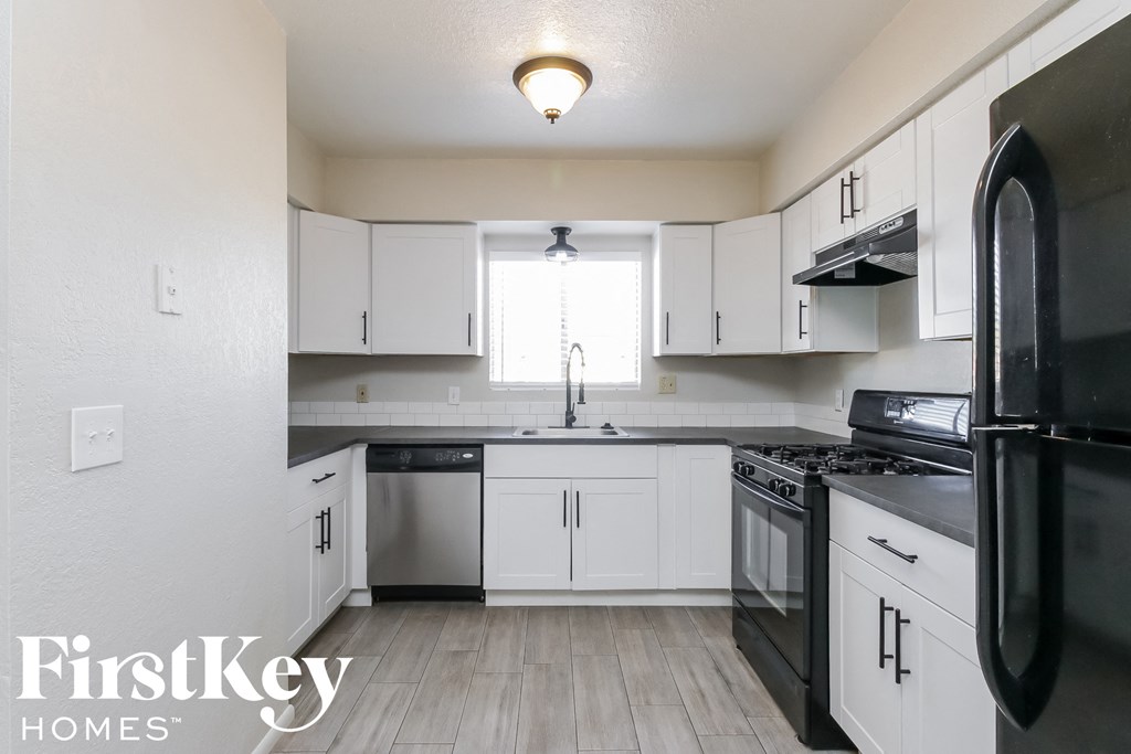 an empty kitchen with white cabinets and black appliances