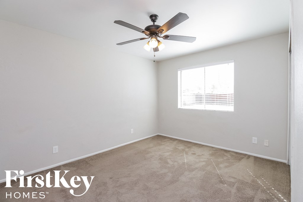 an empty room with a ceiling fan and a window