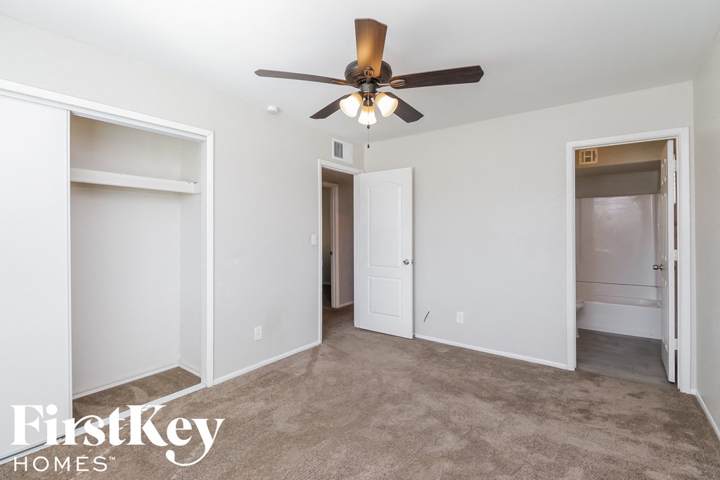 a living room with a ceiling fan and three closets