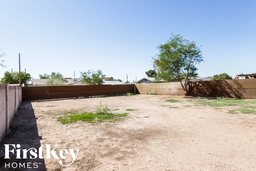 the backyard of a house with a dirt yard and a fence