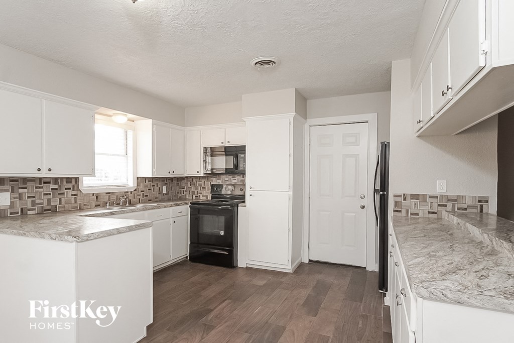 a kitchen with white cabinets and a black stove and refrigerator