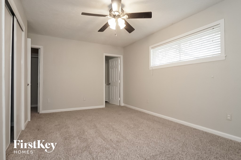the spacious living room with ceiling fan and carpeting