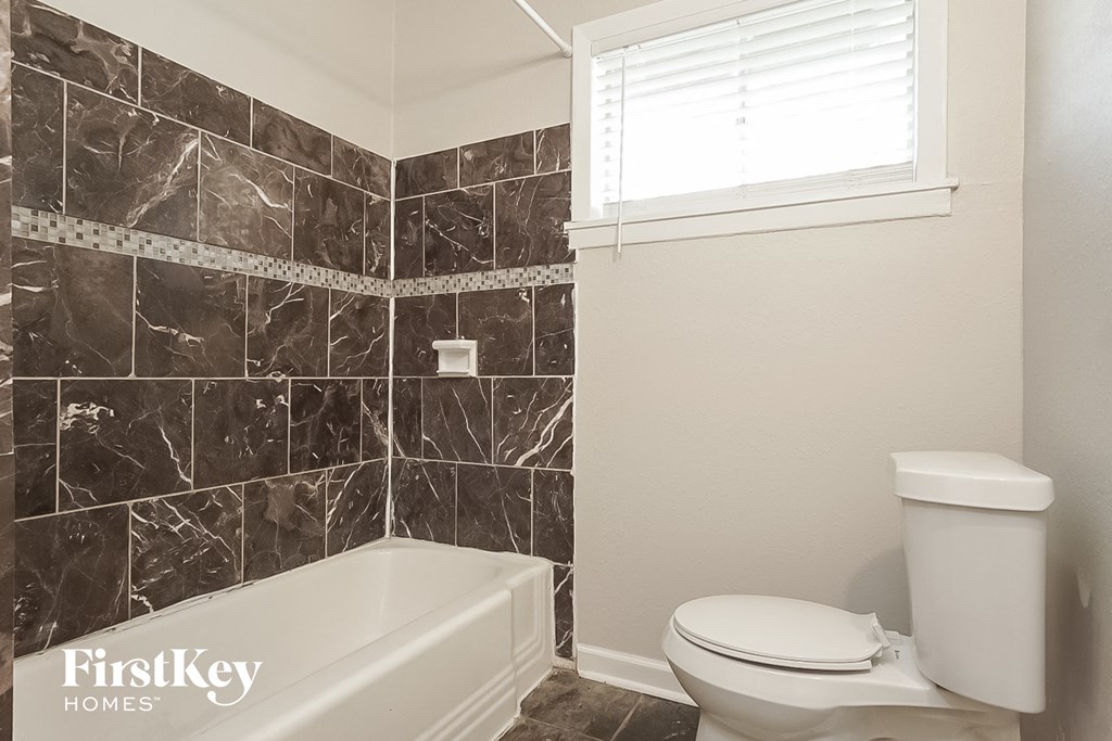 a bathroom with a toilet and a tub and a window
