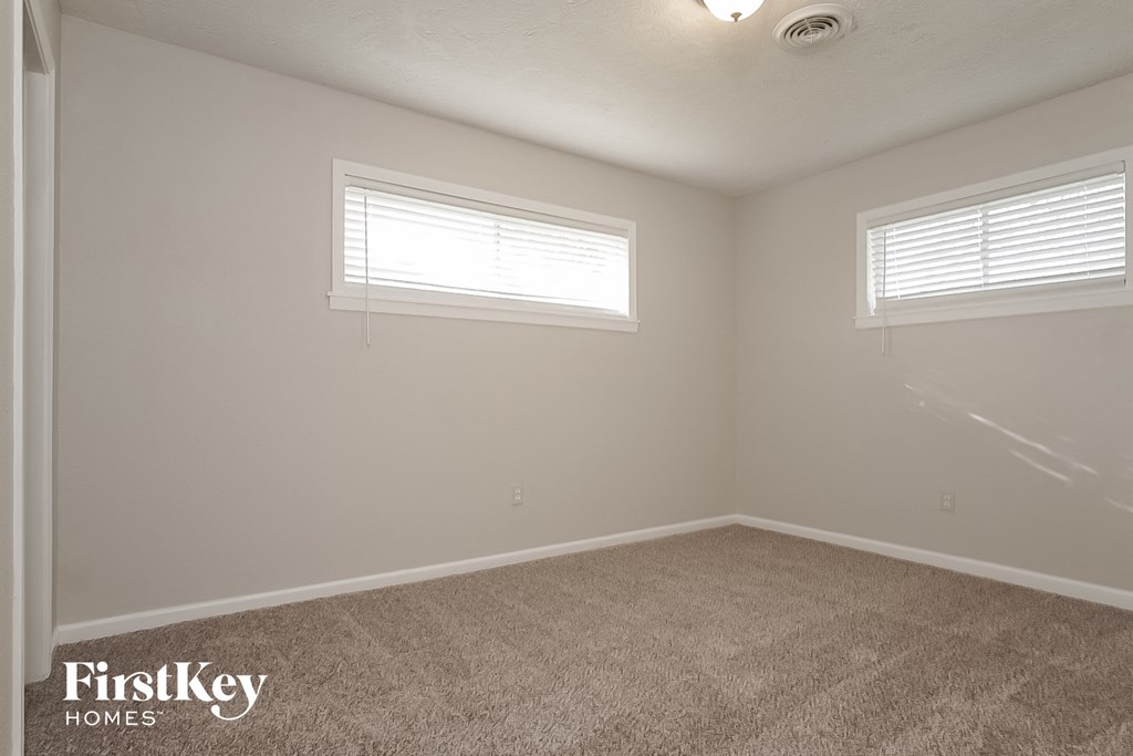 a bedroom with two windows and a carpeted floor