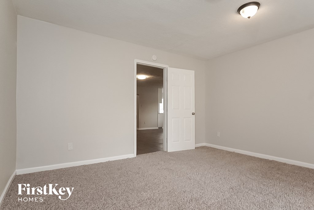 a bedroom with a door to a hallway and a carpeted floor