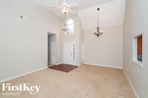 a spacious living room with carpet and a ceiling fan