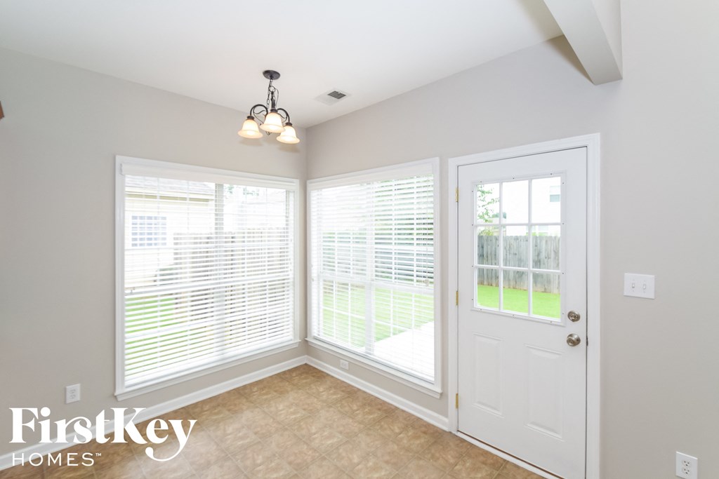 a dining room with three windows and a white door