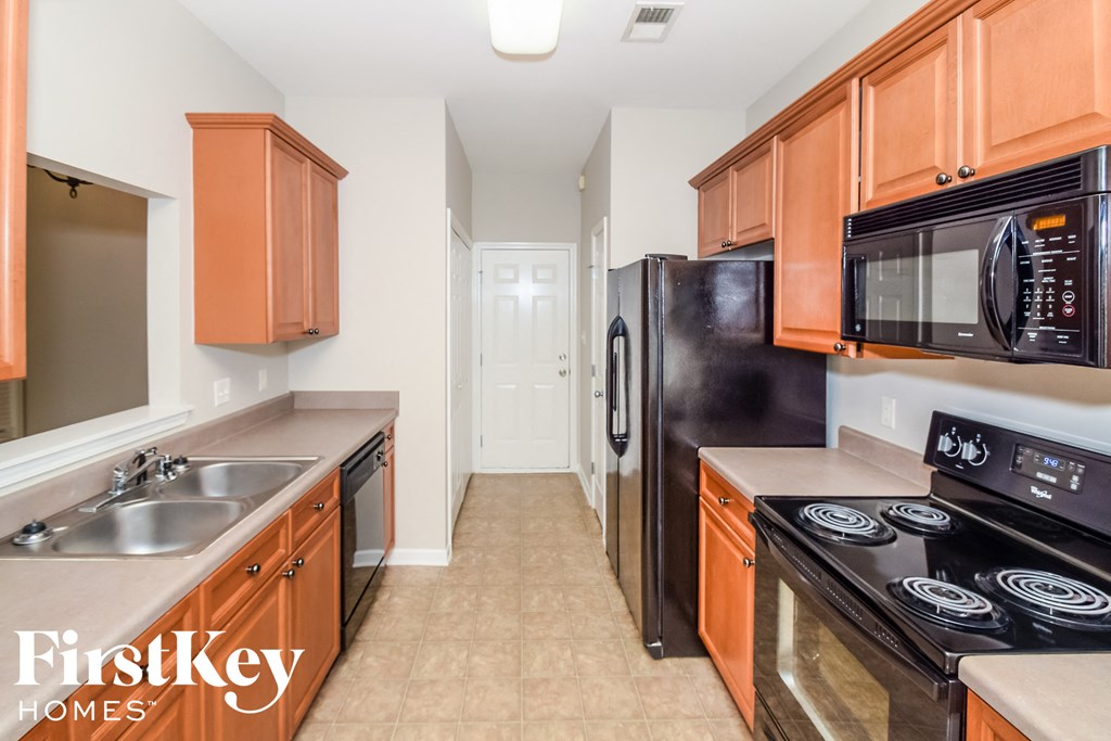 a kitchen with wood cabinets and black appliances and a black refrigerator