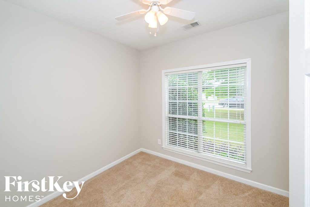 a bedroom with a large window and a ceiling fan