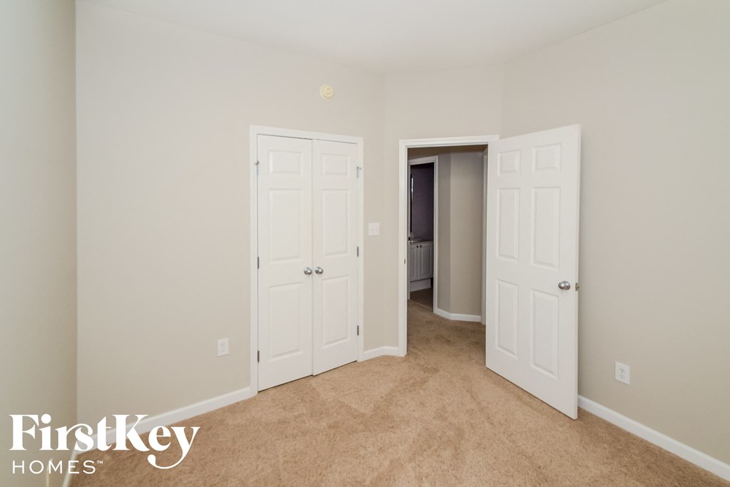 a bedroom with two closets and two doors and a carpeted floor