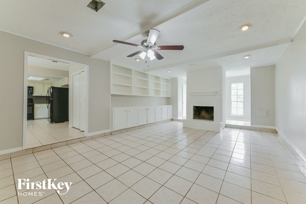an empty living room with a fireplace and a ceiling fan