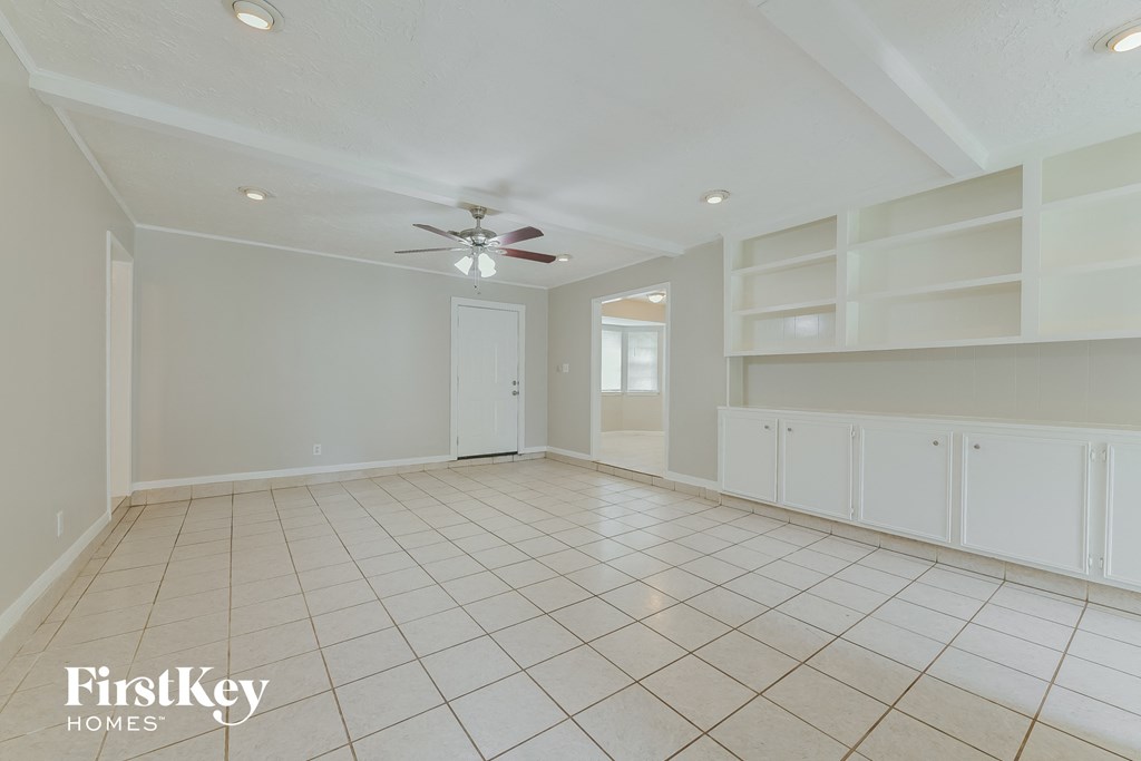 an empty living room with white shelves and a ceiling fan