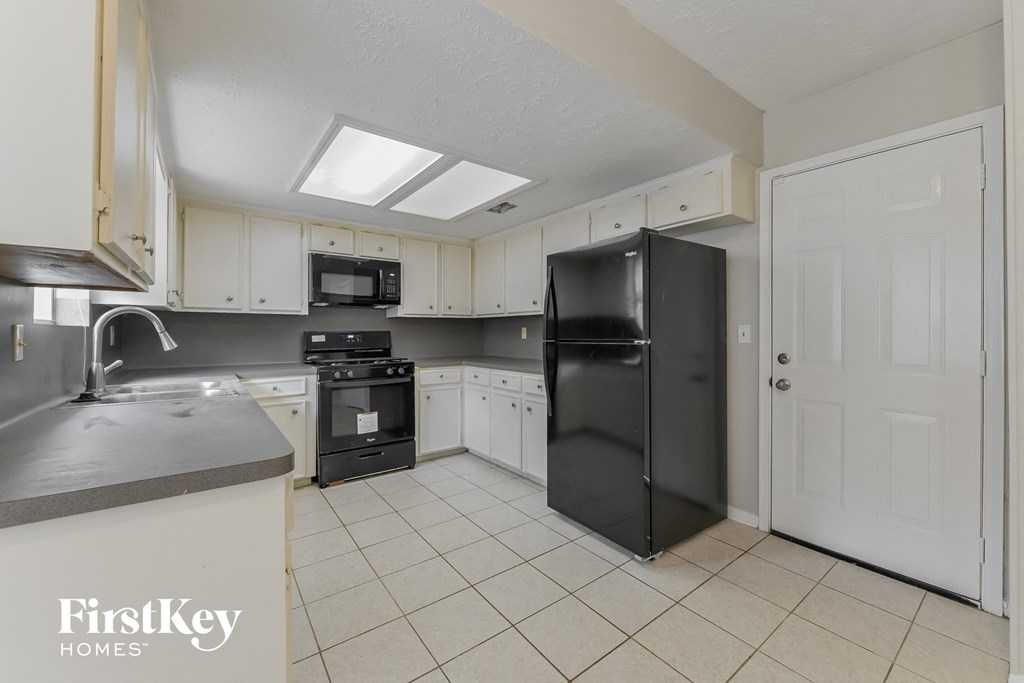 a kitchen with white cabinets and a black refrigerator