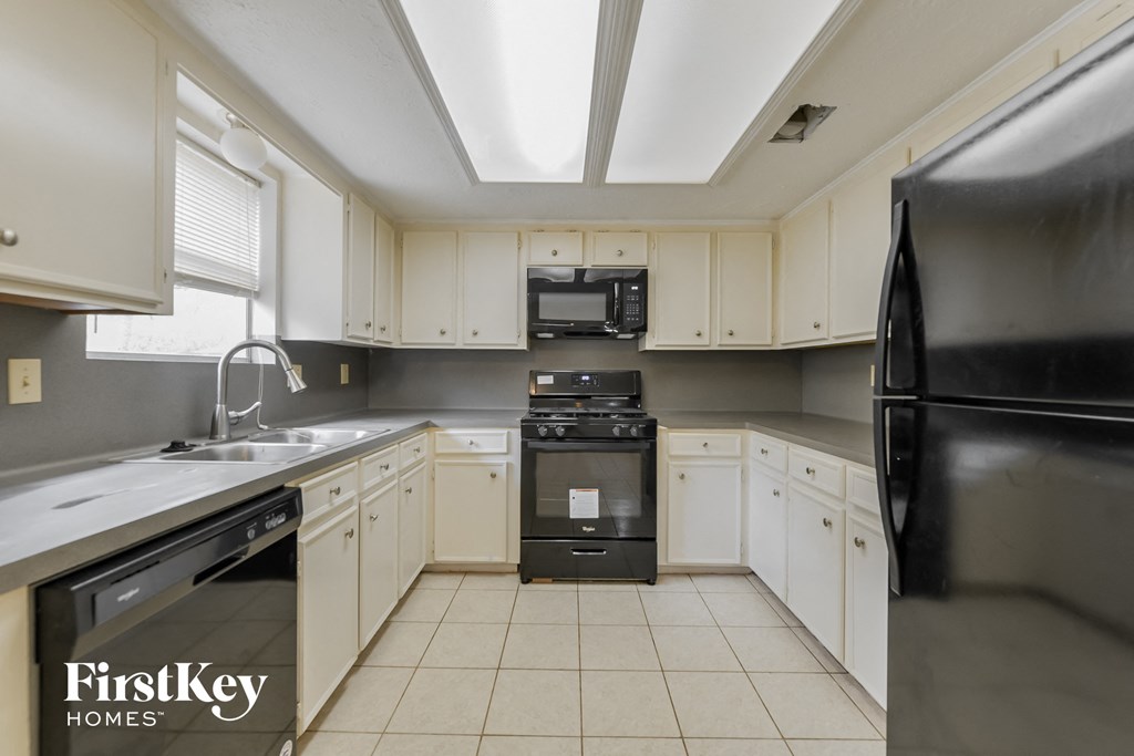 a kitchen with white cabinets and black appliances