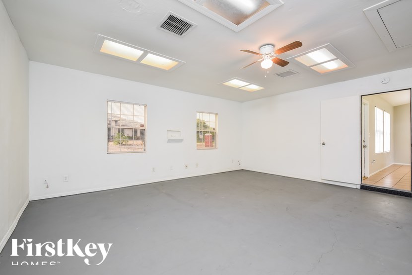 A spacious room with a ceiling fan and lighting fixtures.