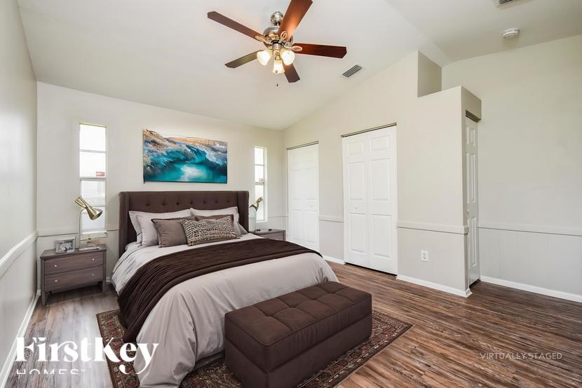 A bedroom with a large bed and a ceiling fan.