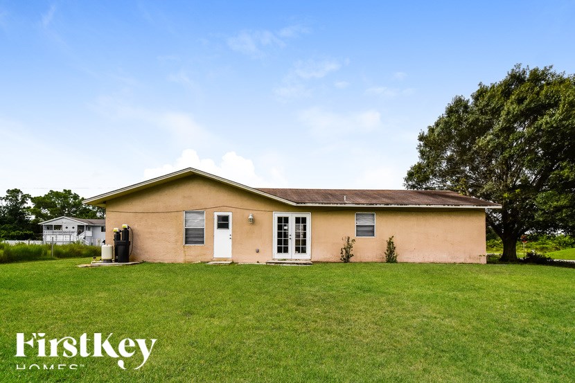 A small house with a white door and windows is surrounded by a grassy lawn.