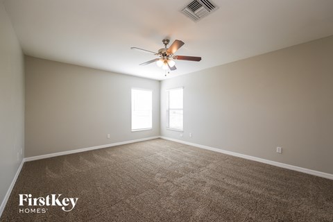 a living room with a ceiling fan and a carpet