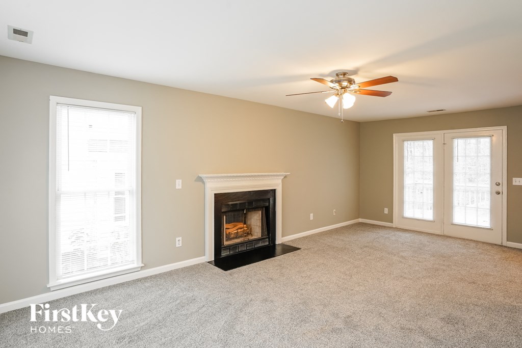 A spacious living room with a fireplace and a ceiling fan.