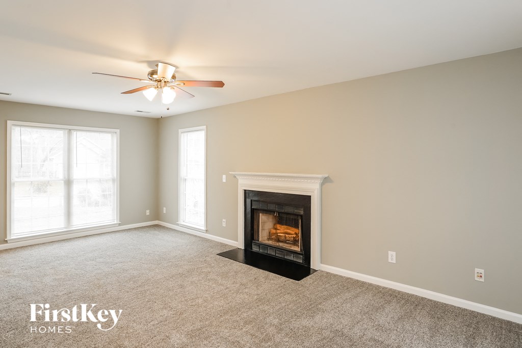 A living room with a fireplace and a ceiling fan.