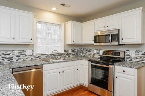 A kitchen with white cabinets and a granite countertop.