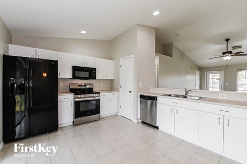 a large kitchen with white cabinets and black appliances