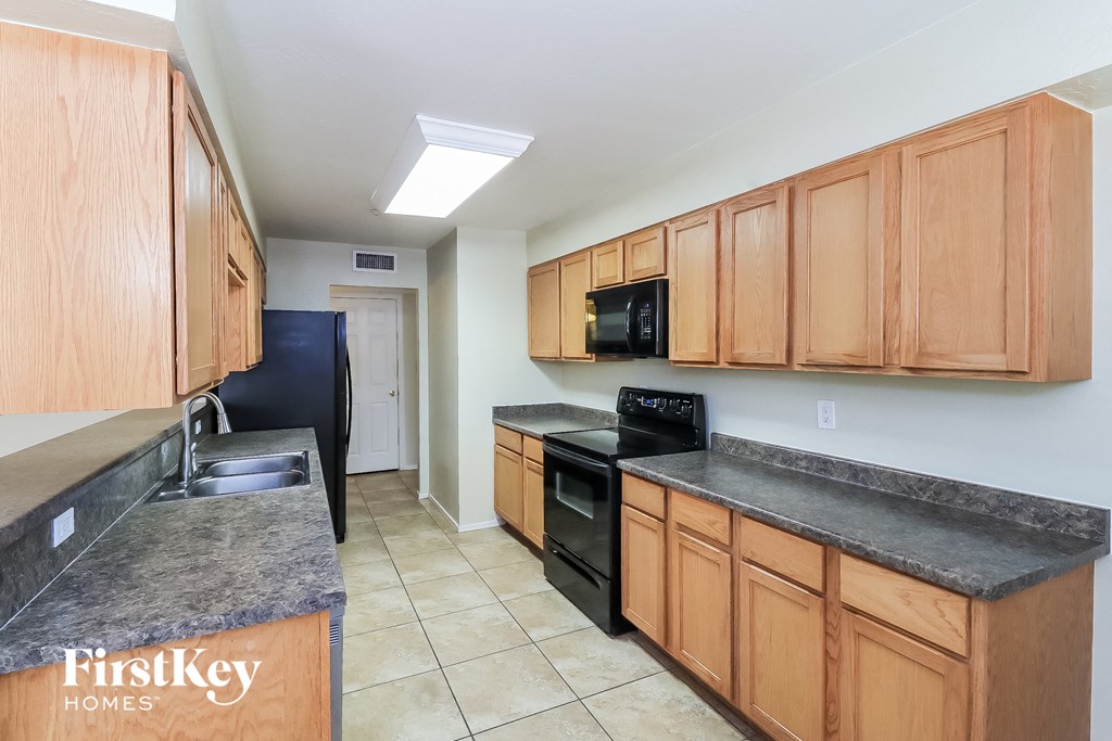 a kitchen with wood cabinets and black appliances and a sink