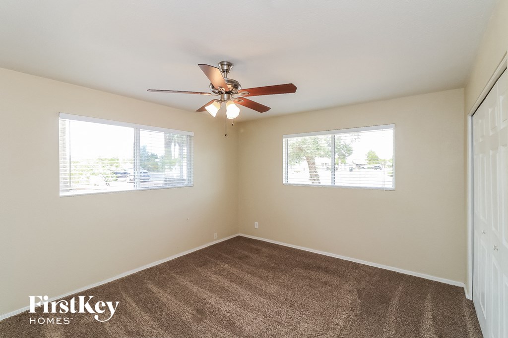 an empty room with a ceiling fan and two windows