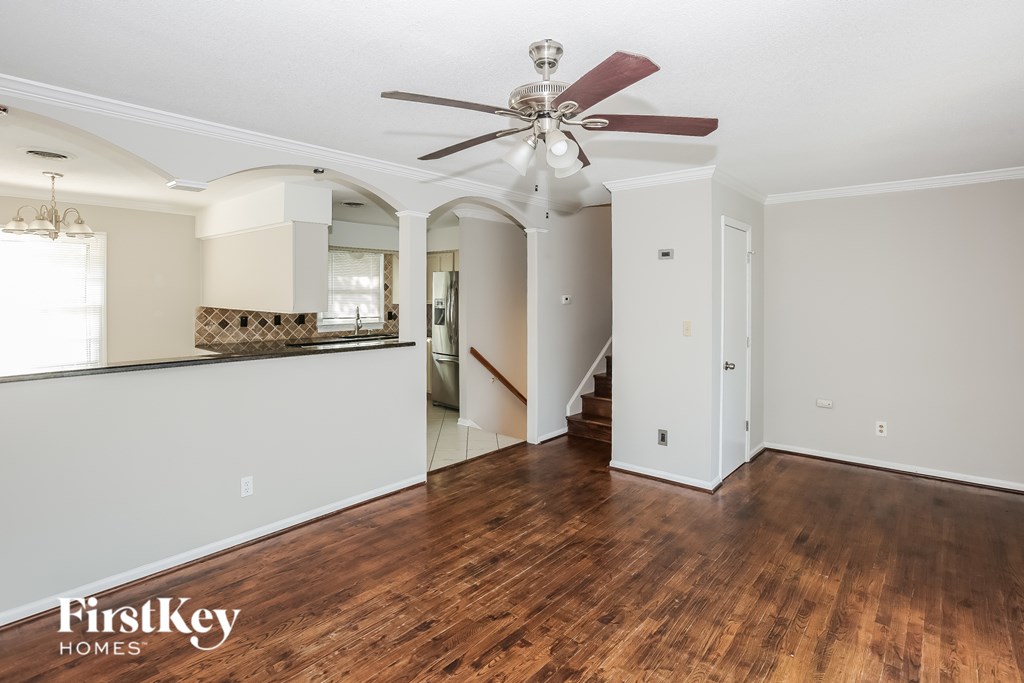 A spacious room with a wooden floor and a ceiling fan.