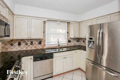 A kitchen with a stainless steel refrigerator and white cabinets.