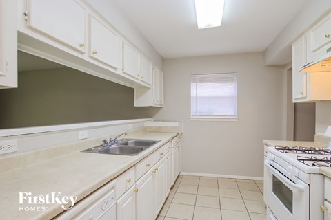 A kitchen with white cabinets and a stove top oven.