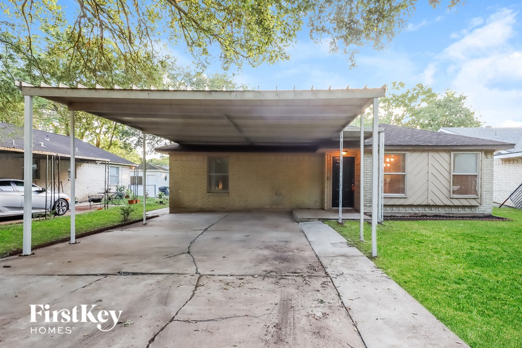 A covered patio area with a concrete floor and a white pergola.